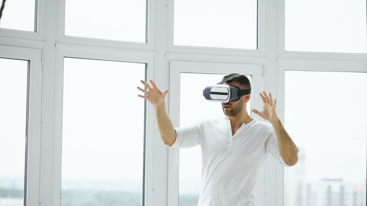 hero-img Adult man exploring virtual reality with VR headset in a bright indoor setting.