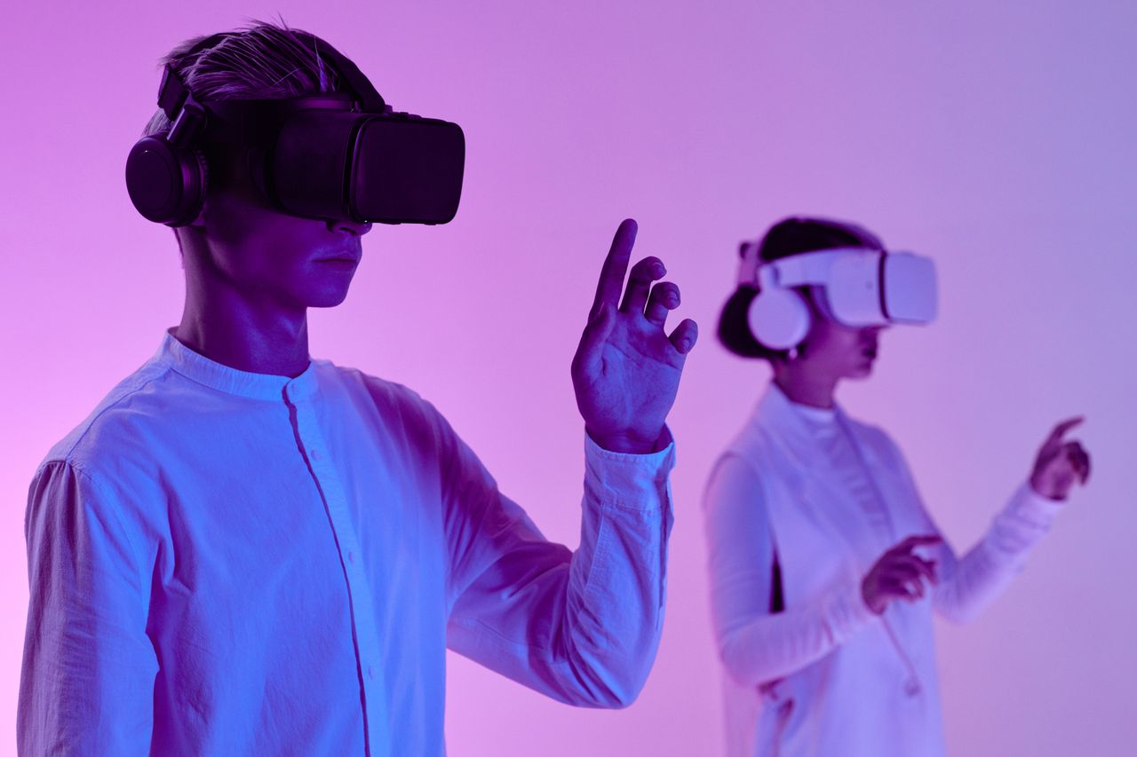 about-01 Two people engage in a futuristic virtual reality simulation with headsets and vibrant lighting.